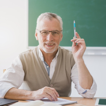 Senior professor with raised hand holding pen in classroom Free Photo