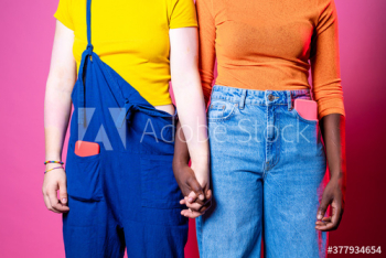 Midsection of young women holding hands standing indoors