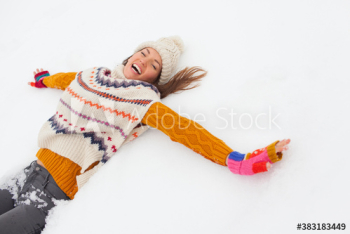 Portrait exuberant young woman making snow angel