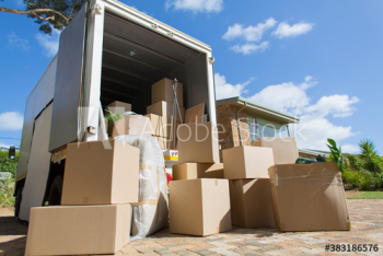 Cardboard boxes outside moving van and house in sunny driveway