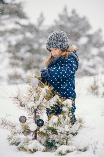 Little girl in a blue hat playing in a winter forest Free Photo