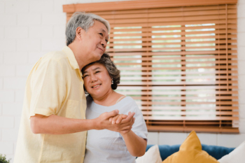 Asian elderly couple dancing together while listen to music in living room at home, sweet couple enjoy love moment while having fun when relaxed at home. Free Photo