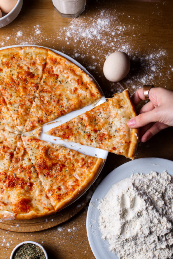 Top  cheese pizza with spices sliced on the wooden table Free Photo