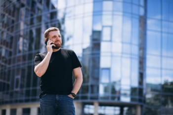 Young business man talking on phone by the skyscraper Free Photo