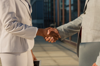 Black businesswoman shaking hands with male partner Free Photo
