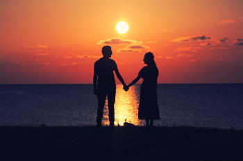 Two people holding hands at sunset Free Photo