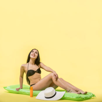Woman in black swimsuit sitting on water mattress and smiling Free Photo