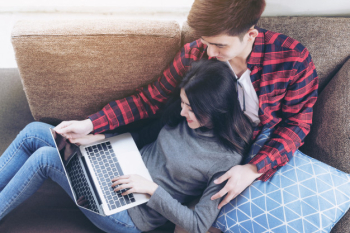 Asian young woman and handsome man sitting on couch using laptop Free Photo