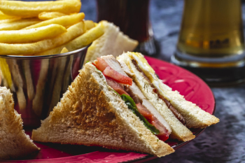 Side view club sandwich with grilled chicken tomato lettuce and french fries on the table Free Photo