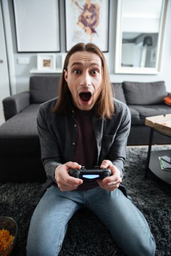 Shocked man sitting at home indoors play games with joystick Free Photo