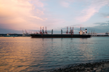 Cargo ship parked at the harbor on a sunny day during sunset Free Photo