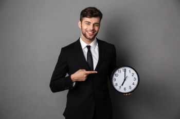 Attractive businessman in classic black suit pointing with finger on big clock, Free Photo