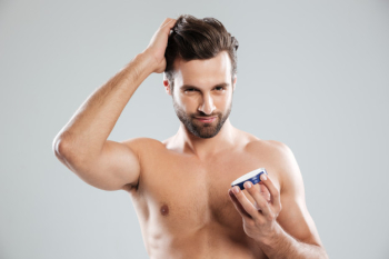 Man straighten hair and holding cream isolated Free Photo
