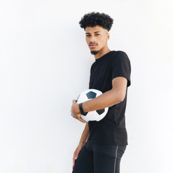 Young black man pressing soccer ball to body Free Photo