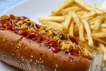 Side view hot dog grilled sausage with caramelized onion cheese ketchup and french fries on the table Free Photo