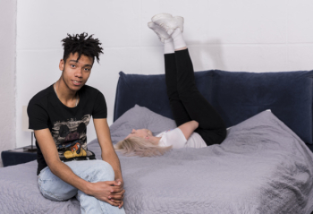 Portrait of a teenage boy sitting on bed and her girlfriend lying on bed at background Free Photo