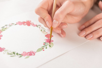 Young artist drawing flowers pattern with watercolor paint and brush on paper at workplace Free Photo