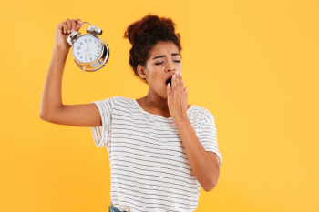 Tired african woman yawns and holding alarm clock Free Photo