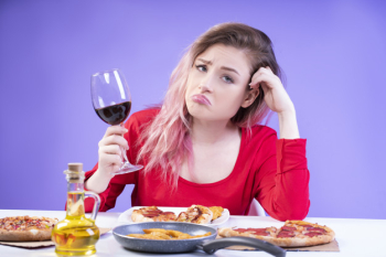 Bored woman in red blouse sits at the table with glass of red wine Free Photo