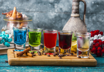 Shot glasses with colorful drinks on wood board Free Photo