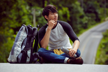 a handsome man with a bottle of water is sitting on the road