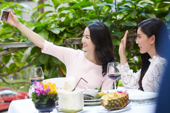 Two girls are raising their hands and taking selfie at a restaurant