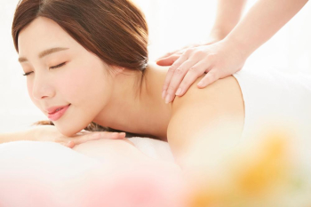 Portrait of a beautiful young woman is relaxing on a massage table and getting shoulder massage