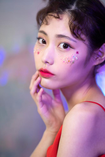 A young beautiful woman is posing in the studio with colorful lighting and bokeh