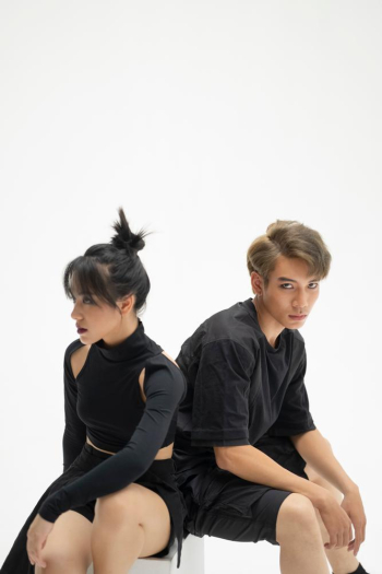 A young couple in black clothes is posing in a cool way