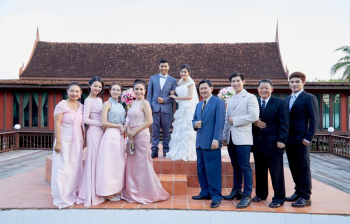 happy newlyweds and their family are standing, smiling and posing