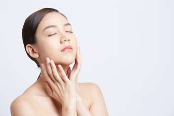 beautiful asian woman is doing massage of face skin on white background