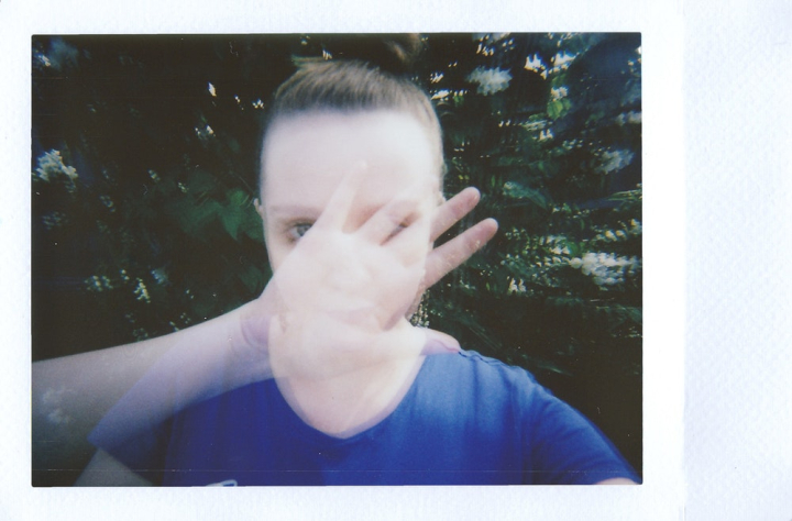 analog,blue shirt,blurred,blurry,double exposure,face,film photography,hand,instant film,looking,outdoors,polaroid,portrait