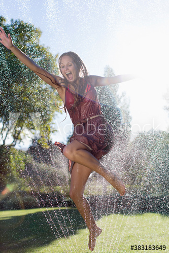 playful,woman,adult,young,jump,sprinkler,sunny,backyard,smile,happiness,enjoy,leisure,lifestyle,vitality,mid-air,motion,dress,water,wet,summer,arms outstretched,fun,carefree,beautiful,barefoot beach,outdoors,day,people,1,alone,adobestock